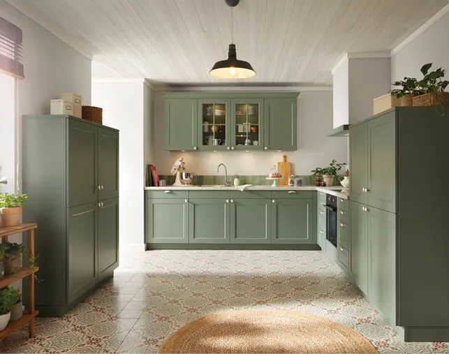 Großzügige Landhausküche in Grün mit Rahmenfronten, Vitrinenschrank und Holzarbeitsplatte. Traditionelles Küchendesign mit viel Stauraum, dekorativen Elementen und gemütlichem Ambiente für stilvolles Kochen und Wohnen.